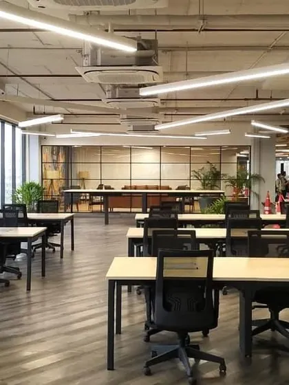 Another angle of the flexible workstation area at VentureX. The industrial-style ceiling with exposed pipes and linear lighting complements the modern, functional furniture.