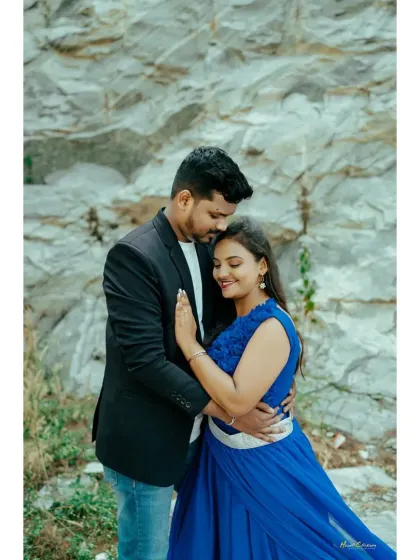 A close-up of a couple in a loving embrace, with the bride in a beautiful blue gown, set against a natural rock wall.