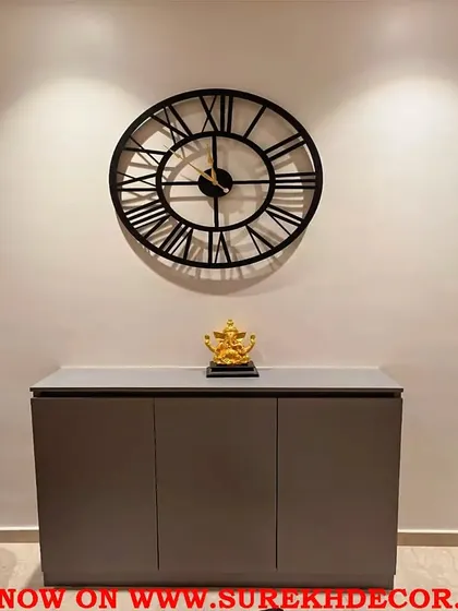 This simple and glamorous vintage wall clock features classic Roman numerals on a large, open metal frame. Its timeless design and antique finish make it a versatile choice for adding a touch of elegance above a console or in a dining area.