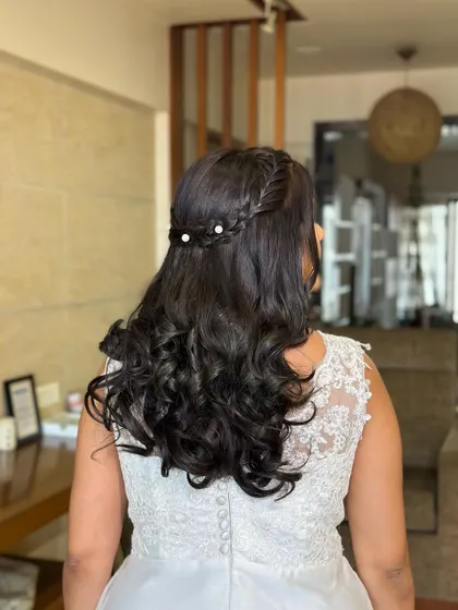 A romantic half-updo for a white wedding. I created a delicate braid crown and added small pearls for a touch of elegance, letting the rest of the hair flow in soft curls.