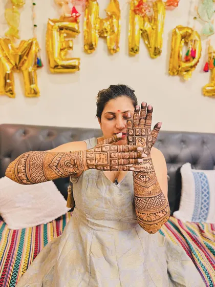 A happy bride showing off her 'Two States, One Heart' mehendi. The joy on her face says it all.