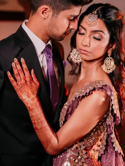 An intimate portrait of the couple, showcasing the bride's stunning mehendi and elegant evening attire. The warm, glowing lights of the Sangeet night create a romantic mood.
