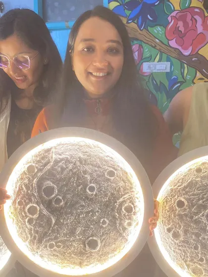 A smiling participant with her finished moon lamp, a unique piece of home decor she made herself.