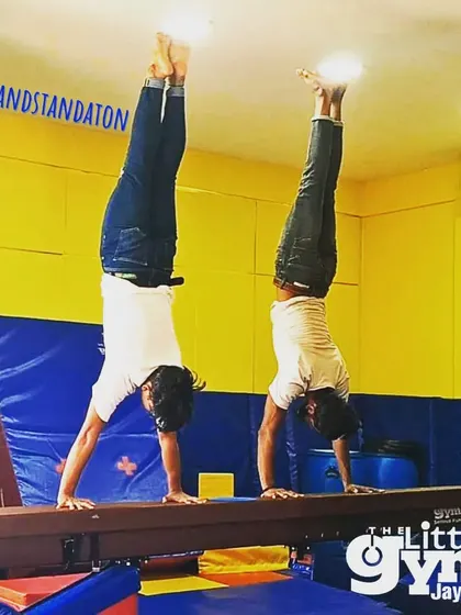 Our instructors demonstrate a perfect handstand on the balance beam, showcasing the high level of skill and precision they bring to their teaching.