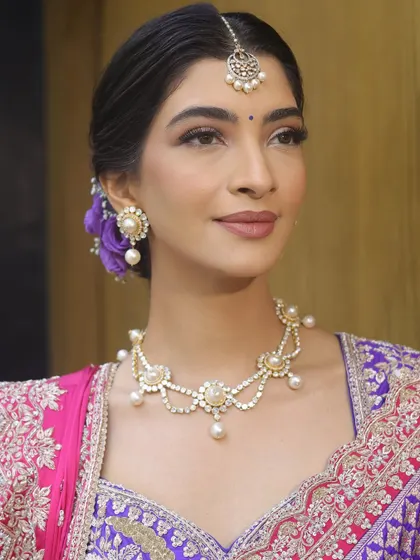 A close-up of the makeup, featuring softly defined eyes, a natural flush on the cheeks, and a muted pink lip.