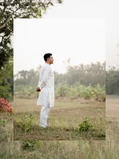 An artistic portrait of the groom-to-be standing in a field, framed to create a modern and clean look.