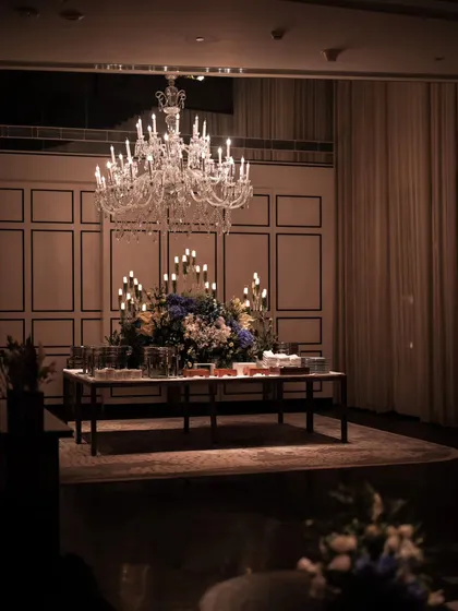 For a 50th birthday, we designed a scene of pure elegance. A magnificent crystal chandelier hangs above a bespoke bar setup, where lush florals and warm candlelight create a sophisticated focal point for the evening's celebrations.