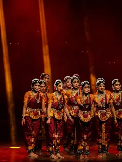 A tight formation from our 'DURGE' production, showcasing the unity of the ensemble. The warm, dramatic lighting highlights the rich colors of the costumes and the focused expressions of the dancers.