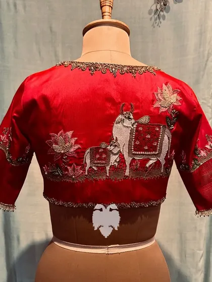 A red silk blouse with a back featuring Pichwai art of a cow and calf.