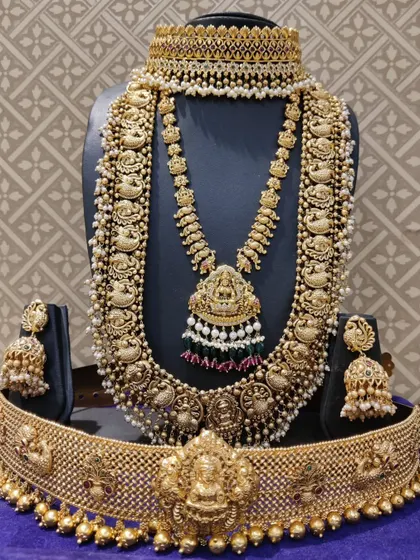 A grand bridal set featuring a Lakshmi choker, a multi-layered pearl and temple haram, and a matching vaddanam.