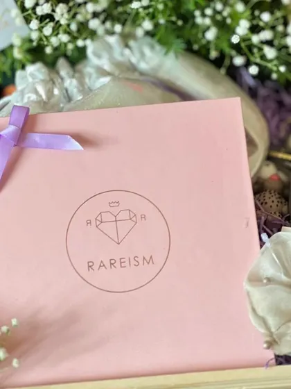 A close-up of an engagement hamper, showing the branded gift bag, a pearl scrunchie, and fresh baby's breath flowers. I focus on combining textures and high-quality items.