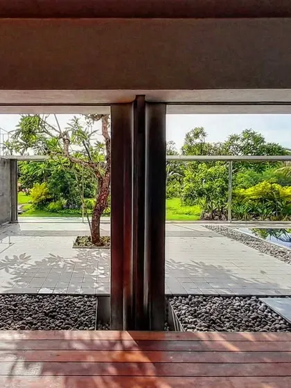 This courtyard design incorporates a small pool and a single tree, creating a serene, minimalist landscape. The space serves as a visual focal point and a natural cooling element for the building.