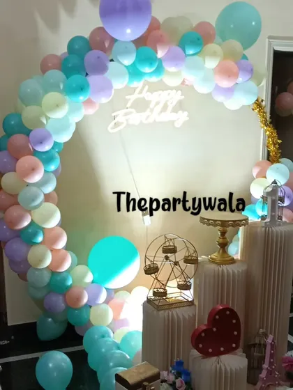 A pastel rainbow balloon ring with a 'Happy Birthday' neon sign.