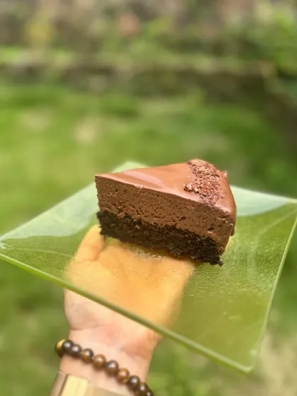 A slice of my decadent triple chocolate mousse cake. It has a rich cake base, a light mousse layer, and a smooth ganache topping.