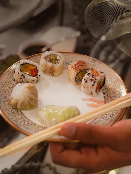 A guest's plate featuring a selection of our sushi and dim sum. This image captures the fine-dining experience we provide, complete with elegant, patterned china.