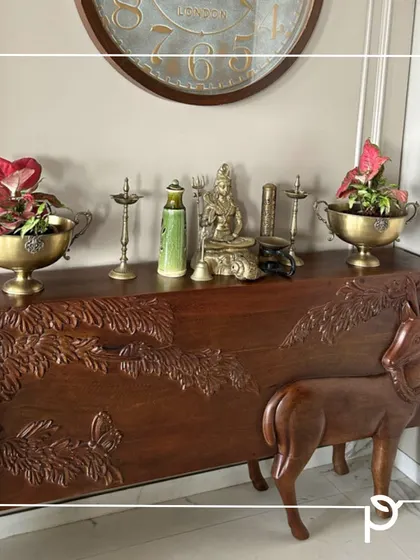 A traditional brass urli is repurposed as a beautiful planter for red Anthuriums, placed on a carved wooden console. We love finding creative ways to integrate plants into our clients' homes and cultural artifacts.