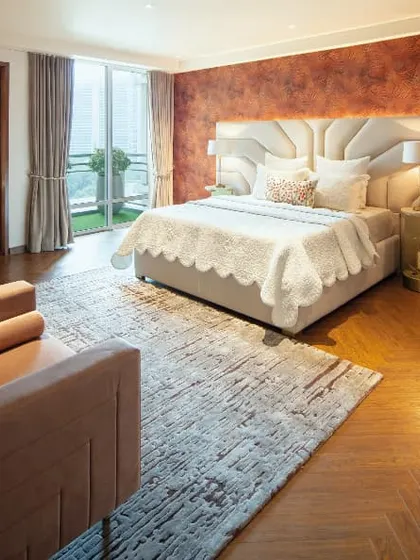 A bedroom with a dramatic textured red accent wall and striped wooden flooring, showcasing a bold and eclectic style.