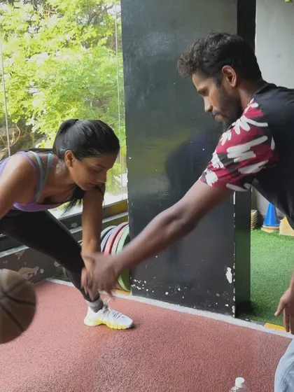 A trainer works with a client on basketball dribbling drills, showcasing our ability to provide sport-specific training.