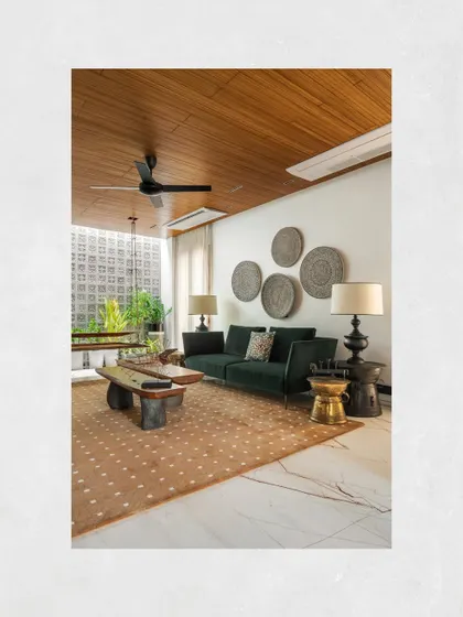 The formal living area, where a wooden ceiling and a plush, textured rug add warmth to the cool marble floors and green sofa.