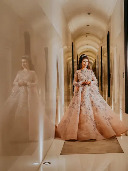 A stunning portrait of the bride in her fairytale gown, captured in a beautifully lit hallway. The reflection on the polished walls adds a layer of elegance and depth to the image.