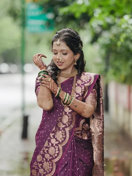 An elegant portrait of the bride-to-be. She looks graceful in her purple silk saree, with traditional jewelry and soft, natural-looking makeup.