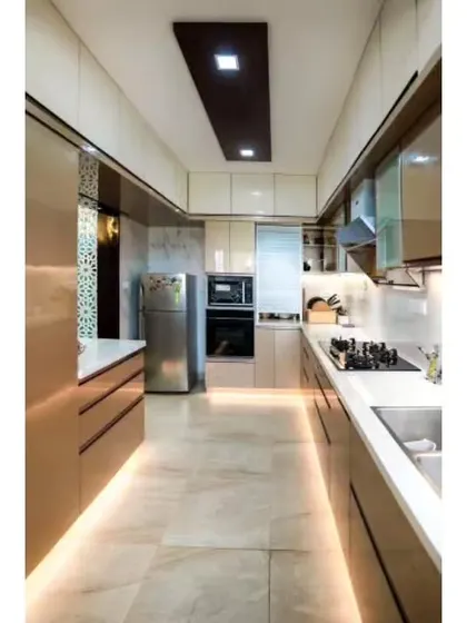 A luxurious parallel kitchen with glossy beige cabinets and integrated appliances. We used under-cabinet strip lighting along the base of the cabinets to create a floating effect and provide ambient light.