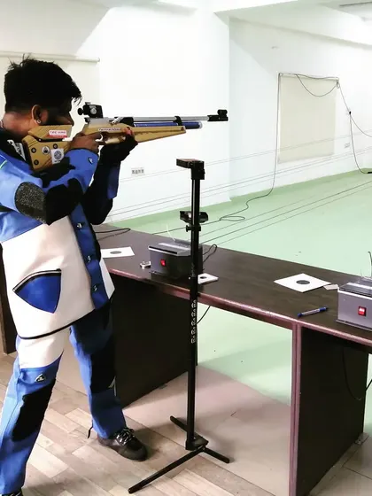 A shooter takes aim during a practice session, showing the concentration and steady form required for 10-meter air rifle shooting.