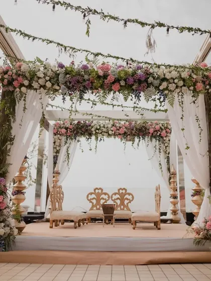 A rustic yet romantic mandap setup at the Intercontinental Marine Drive. The combination of a wooden frame, lush greenery, and pastel florals creates an intimate and beautiful atmosphere with an open sky view.