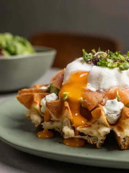 A close-up of the poached egg on our Smoked Salmon Waffle, its golden yolk cascading over the delicate salmon and waffle.
