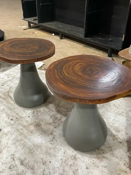 A pair of unique side tables with a sculptural grey base and a textured dark wood top.