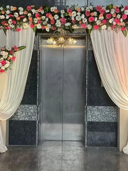 Even an elevator entrance can be transformed into a grand statement. We framed this entrance with elegant drapes and a beautiful floral arrangement, complete with a chandelier.