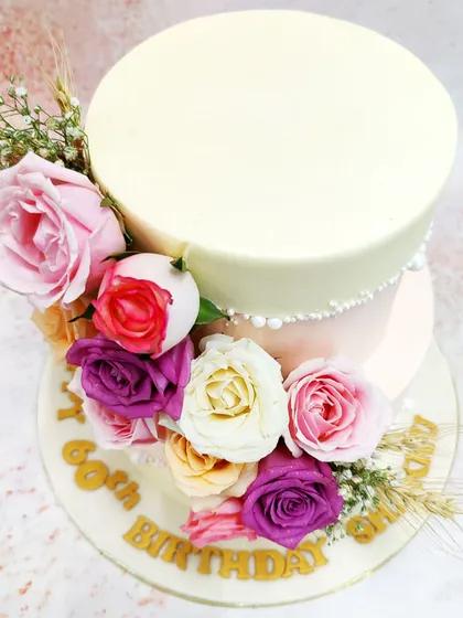 This two-tiered floral fault line cake is the epitome of modern elegance. A cascade of fresh roses in shades of pink, purple, and cream appears to burst through the delicate pink and ivory tiers, creating a design that is both dramatic and romantic.