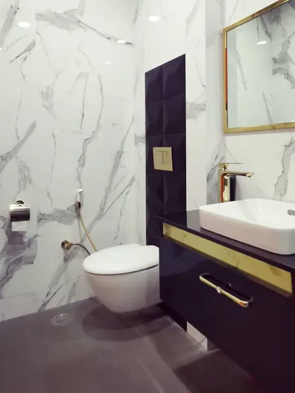 The executive washroom, featuring full-height marble-patterned tiles and contemporary black and gold fixtures. We believe high-quality design should extend to every part of a facility.