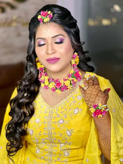 A beautiful Haldi look featuring pink and purple eye makeup and stunning floral jewellery.