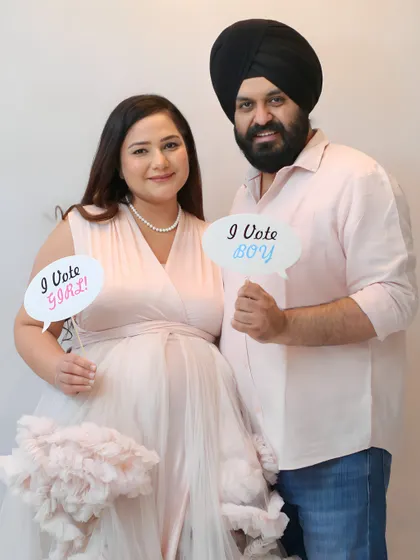 A fun gender reveal moment during a maternity shoot. The couple holds up "I Vote Boy" and "I Vote Girl" signs, adding a touch of playfulness to their session.