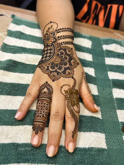 An elegant back-of-hand design with a floral mandala and a delicate chain connecting to the finger. A very graceful and jewelry-like pattern.