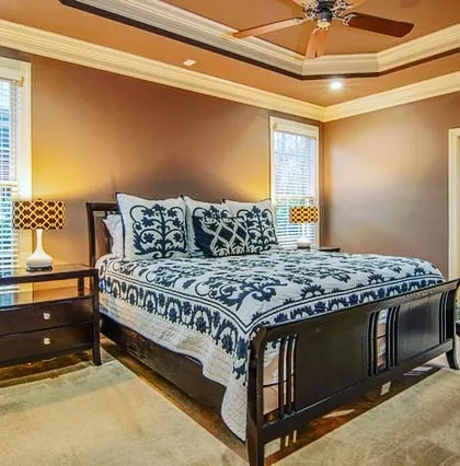 A master bedroom painted in a warm, earthy brown. The paint complements the dark wood furniture and creates a cozy, traditional feel.