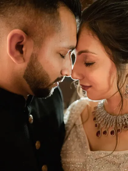 A quiet, romantic moment with foreheads touching. We capture the calm within the storm of a big celebration.