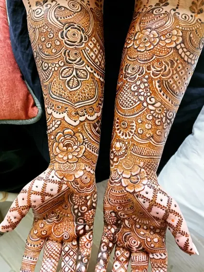 A stunning example of a full-coverage design with a mix of bold flowers and delicate, lace-like patterns. The symmetry between the two hands is a hallmark of a well-executed bridal mehendi.