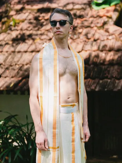 A stylish groom in a traditional mundu, posing with sunglasses. This shot blends cultural attire with modern cool, creating a unique and memorable portrait.