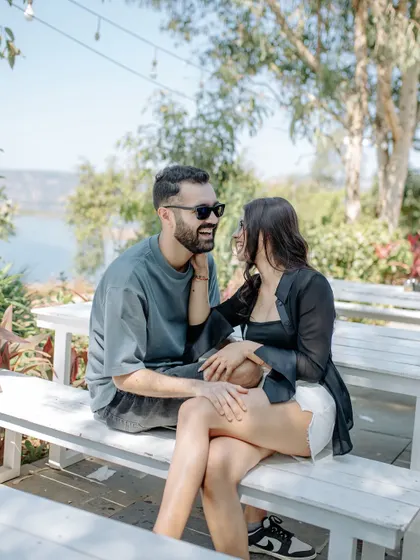 Laughter and sunshine. This candid pre-wedding shot captures a moment of pure joy and connection, with the couple sharing a laugh in a beautiful outdoor setting.