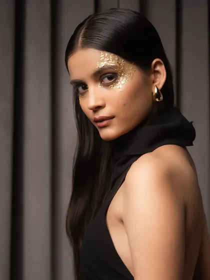A close-up beauty shot with dramatic gold-leaf makeup. This image focuses on the model's expression and the detailed makeup artistry, ideal for a beauty or editorial portfolio.