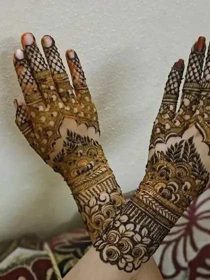 Two hands with heavy 'jaal' and floral patterns, a classic choice for festive occasions.
