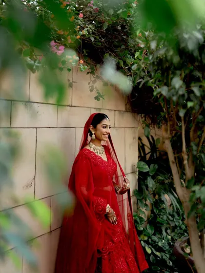 A beautiful smiling portrait of the bride, framed by lush greenery. Her happiness is radiant in this candid moment.