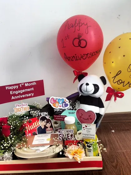 A sweet hamper to celebrate a one-month engagement anniversary. This compact tray includes a small bouquet of roses, a panda toy, a protein drink, and snacks, showing that every milestone matters.