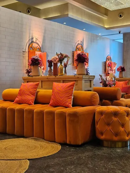 A wide view of the plush, modern orange lounge seating at the Sangeet. The combination of contemporary furniture with traditional decor elements showcases how our space can be adapted to unique, fusion themes.