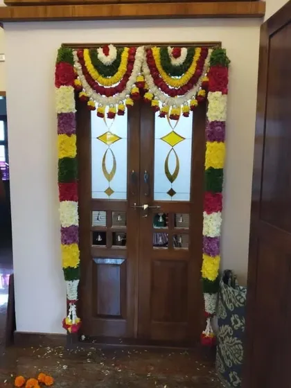 A double door for a pooja room decorated with colorful flower torans. This adds a festive and traditional feel to the home.