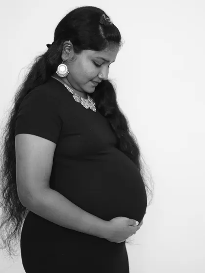 A classic black and white maternity portrait. The simplicity of the pose and monochrome tones create a timeless and artistic image that focuses on the beautiful shape of the baby bump.
