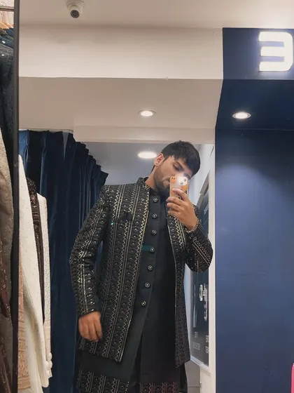 An influencer's mirror selfie, capturing the detailed silver embroidery on a black bandhgala jacket during our store launch.