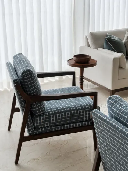 A detail shot of the stylish armchairs in our English-inspired living room. The dark wood and checked fabric provide a classic touch that complements the modern, neutral surroundings.